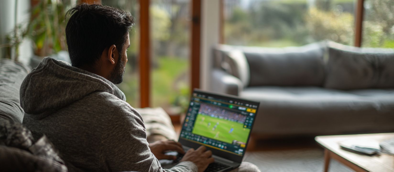 OKLA Bet – The number one choice for online sports betting in Bangladesh Sports fan placing live bets on football match using OKLA betting platform at home